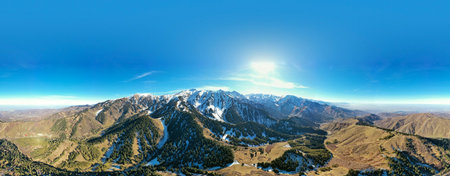 Panoramic view of mountainside lit by setting sun in the rocky mountains. The glow of the sun illuminates the fall colors, along with the first snow found high up in the mountain peaksの写真素材