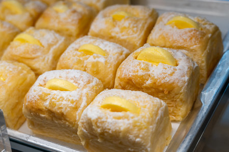 Lush buns sprinkled with powdered sugar and a piece of butter, fruit, cheese beautiful in a bakery window.の写真素材