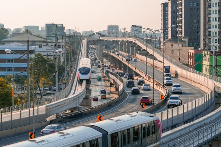 Urban view railway tracks suburban electric monorail trains rushing along among high buildings, cars and trucks drive dense traffic highway with exits turns. Modern infrastructure transport travel.の写真素材