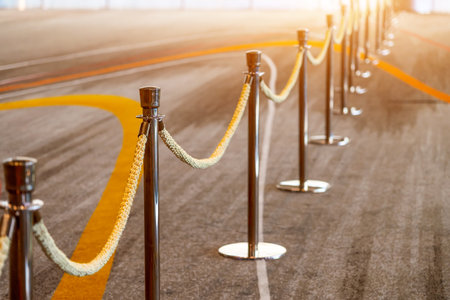 Gold support posts with yellow brown velvet textile fabric rope fencing, access control, vip only.
