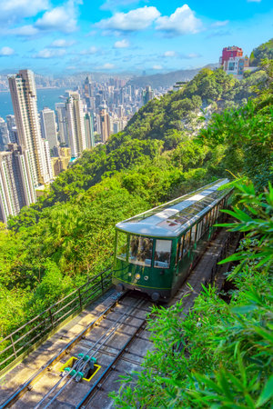 The famous green tram on the slope of Victoria Peak in Hong Kong passes, lifting visitors to the observation deck at the top.の写真素材