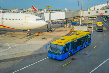 View of the apron of a major airport transport hub. A wide-body airliner is attached to the terminal, a bus with passengers is passing by to board the plane, airport infrastructureの写真素材