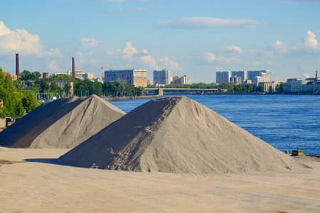 Heaps of gravel, crushed stone, pebbles in the port, a large storage of bulk minerals and stones on the shore of the port in the city.の写真素材
