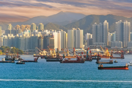 View of ships barges with cranes in Hong Kong city bay with buildings and mountains in the backgroundの写真素材