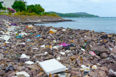 Catastrophic scale of plastic pollution tropical seas. Many lot of trash on beach stones rocks embankment protection breakwater, plastic cups, bags nets fishing picturesque Asia landscape around.の写真素材