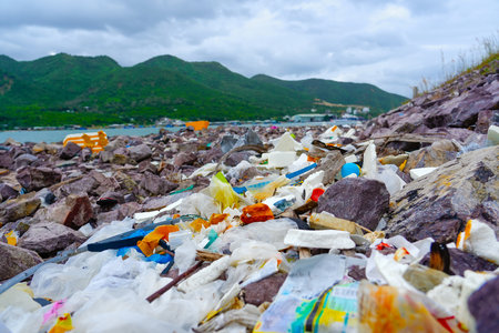 Catastrophic scale of plastic pollution tropical seas. Many lot of trash on beach stones rocks embankment protection breakwater, plastic cups, bags nets fishing picturesque Asia landscape around.の写真素材
