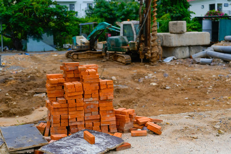 The bucket of a mini loader, which carries a fully loaded red brick down the street. An example of solving problems with low costs and with the use of ingenuity, ways to use a mini loader.の写真素材