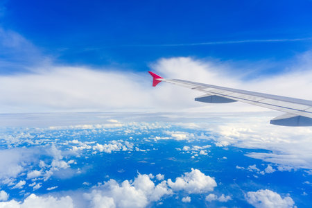 Wing view airplane cirrus, stratus and cumulus clouds surrounded by blue tropospheric haze.の写真素材