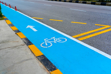 Blue Bicycle Path on the Side of a City Highway Demarcated with Yellow Lines.の写真素材