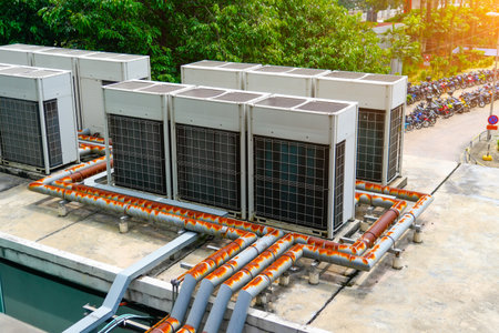 The external units of the commercial air conditioning with rusty utility pipes requiring replacement and ventilation systems are installed on the roof of industrial building.の写真素材