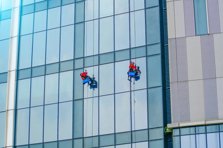 Work on the heights. Industrial mountaineering, group of workers cleaning windows service on high rise buildingの写真素材