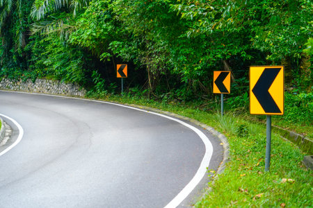 Sharp turn sign yellow warning attention road, serpentine. Car winding road in beautiful forestの写真素材