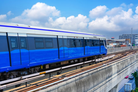 High speed electric train rides on a sky bridge over a city highway road junction.の写真素材