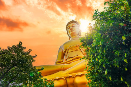 Big Buddha Dhammakaya Tep Mongkol Buddha of Paknam Bhasicharoen temple in Thonburi orange sun sky.の写真素材