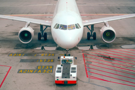 The tow tractor pushes the plane for towing and engine start, front view.の写真素材