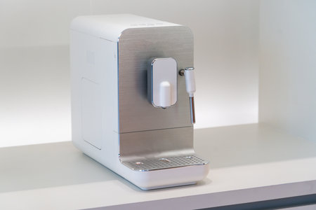 A sleek coffee machine occupies a well-lit space on a countertop. Its modern design complements the minimalist kitchen decor, making it a functional centerpiece for coffee enthusiasts.の写真素材