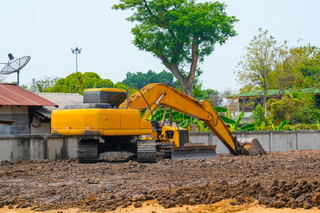 Excavator on the ground of a construction site with a raised bucket rural landscape around.の写真素材