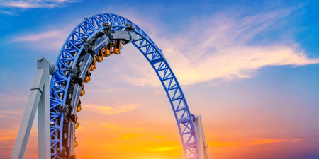 Roller coaster cart and people riding it goes through a loop upside down sky clouds vibrant color sunsetの写真素材