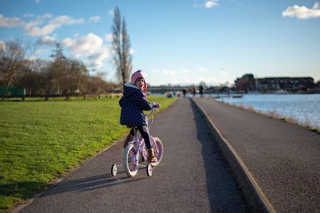 Child on the bike on the path by the riverの写真素材
