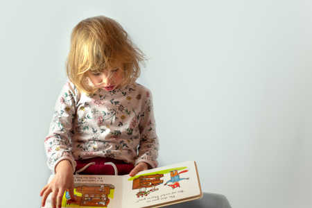 preschool girl reading book studio portrait on clean backgroundの写真素材