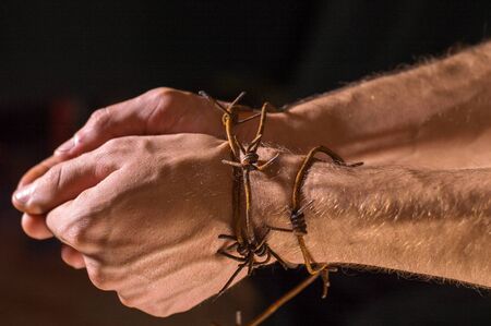 hands on a dark background wrapped in rusty barbed wireの写真素材