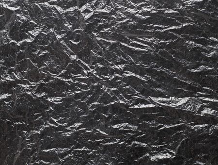 Crumpled black polyethylene texture with highlightsの写真素材