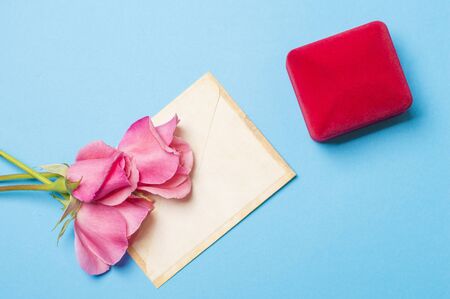 ring in a box with an envelope and roses on a blue backgroundの写真素材