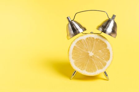 lemon in the form of a clock on a yellow backgroundの写真素材