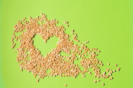 pea groats on a green background, scattered in the shape of a heartの写真素材