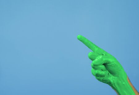 hand in green paint thumbs up on a blue backgroundの写真素材