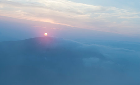 sunset in the mountains, mountains in the clouds in a hazeの写真素材