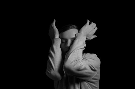 young man on a black background in a dramatic expressive poseの写真素材