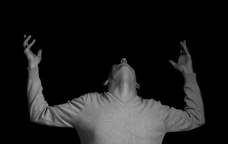 young man on a black background in a dramatic expressive poseの写真素材