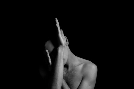 young man on a black background in a dramatic expressive poseの写真素材
