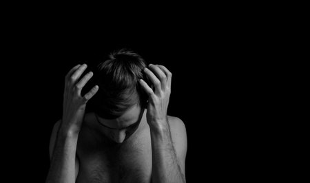 young man on a black background in a dramatic expressive poseの写真素材