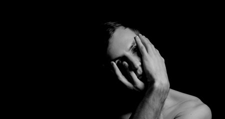 young man on a black background in a dramatic expressive poseの写真素材