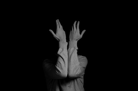 young man on a black background in a dramatic expressive poseの写真素材