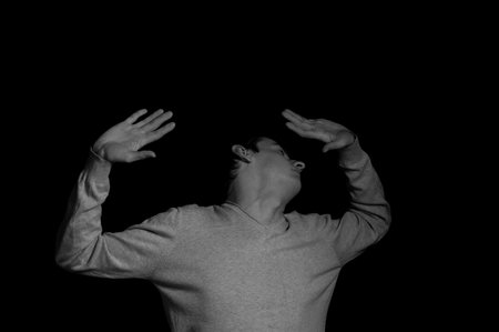 young man on a black background in a dramatic expressive pose
