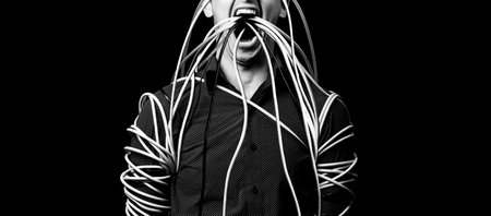 a man in a shirt wrapped the wires, the wires go out of his mouthの写真素材