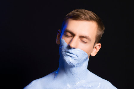 portrait of a guy body and part of the face in blue paintの写真素材