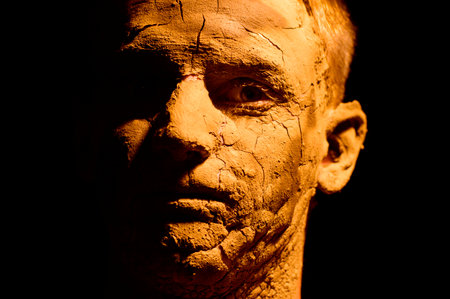 portrait of a guy on a black background with cracked skinの写真素材