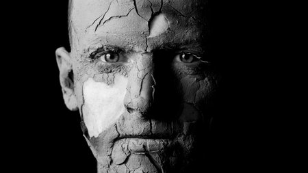 portrait of a guy on a black background with cracked skinの写真素材