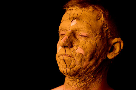 portrait of a guy on a black background with cracked skinの写真素材