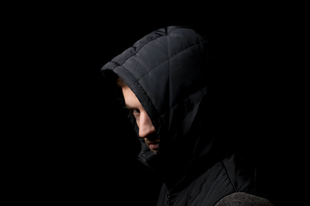 young man in a hood on a black background