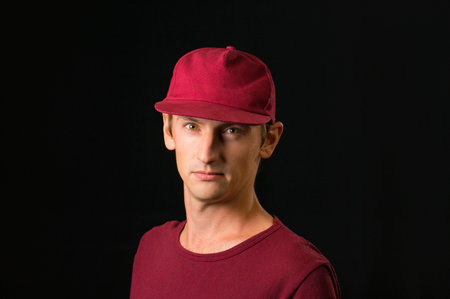 man on a black background in a burgundy cap and t-shirtの写真素材