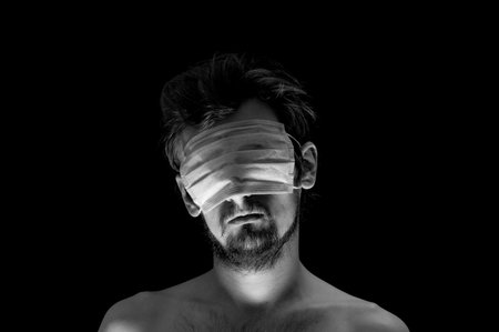 portrait of a guy on a black background, a mask on his eyesの写真素材