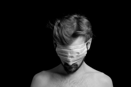 portrait of a guy on a black background, a mask on his eyesの写真素材