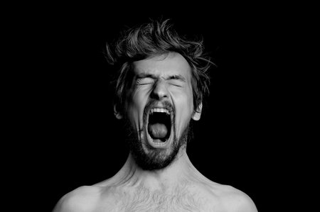 portrait of a guy with a beard and tousled hair on a black backgroundの写真素材