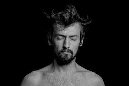 portrait of a guy with a beard and tousled hair on a black backgroundの写真素材