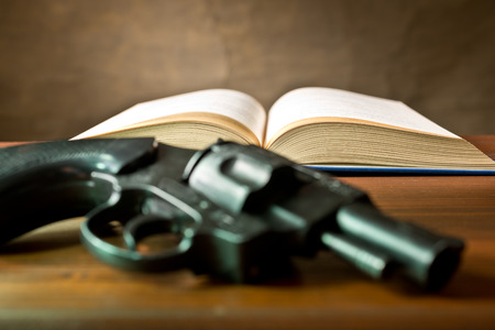 a open book and hundgun on the brown tablleの写真素材